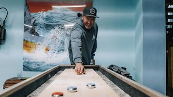 Una persona jugando al juego de bolos en un espacio con un gran mural de una ola en la pared.
