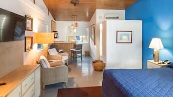 A hotel room with a bed, a desk, a chair, a lamp, and a television.