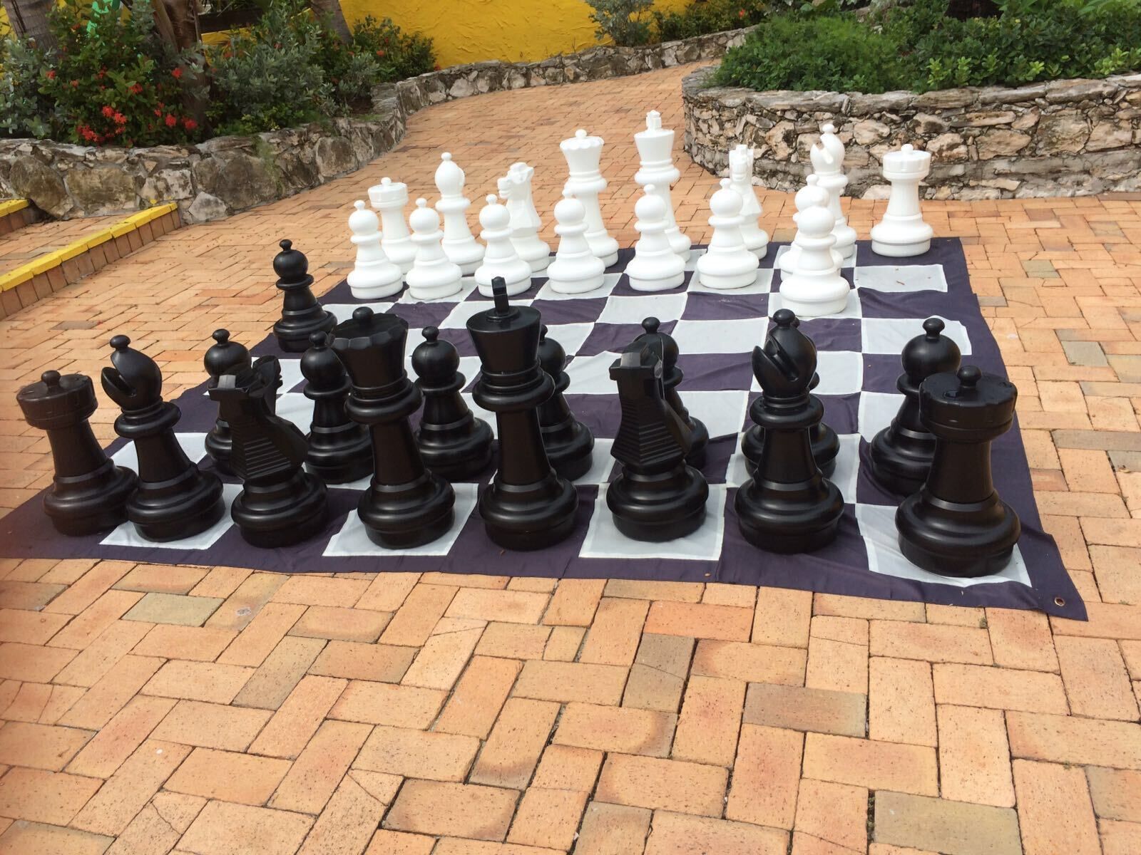 A chessboard set up outdoors with black and white pieces.