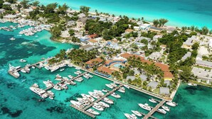 An aerial view of a marina with numerous boats docked, surrounded by residential buildings and lush greenery. - Bimini Big Game Club Resort & Marina (Alice Town)