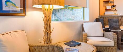 A cozy room with wicker furniture, a lamp, and a framed picture of a fish.