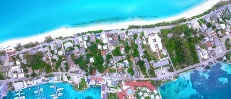 An aerial view of a coastal town with a marina, buildings, and clear blue waters.
