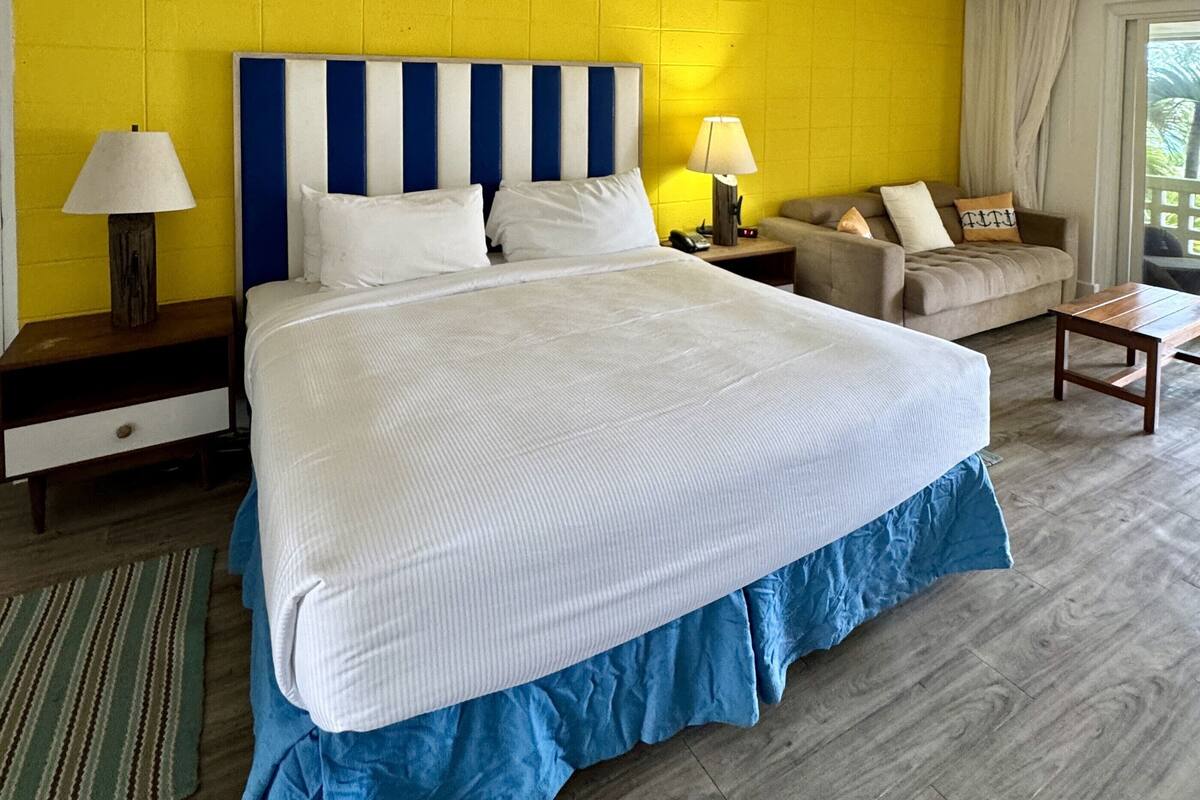 Ein Hotelzimmer mit einem großen Bett, zwei Nachttischen, einem Sofa und einem kleinen Tisch.