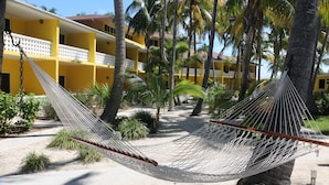A hammock between palm trees in a courtyard with yellow buildings in the background. - Bimini Big Game Club Resort & Marina (Alice Town)