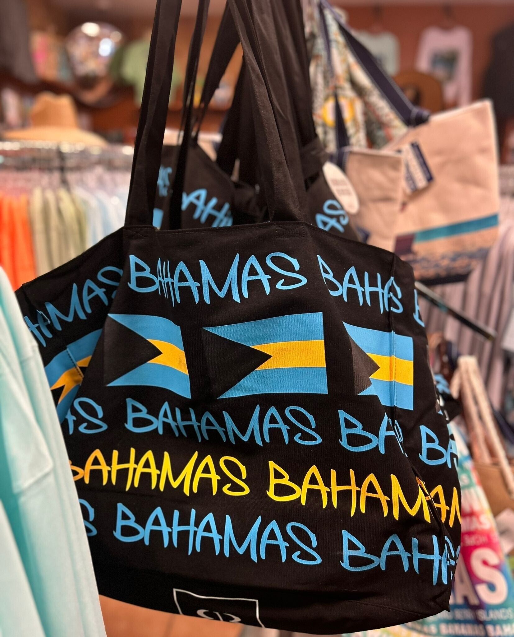 A display of black bags with 'Bahamas' written in blue and yellow.