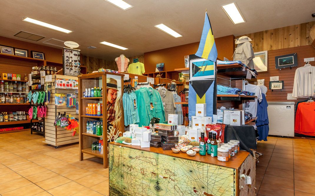 Un magasin où l’on trouve divers articles exposés sur des étagères et présentés sur un comptoir, notamment des vêtements et des souvenirs.