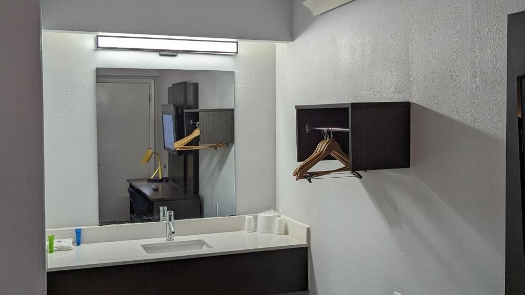 A modern bathroom with a large mirror, a white sink, and a towel rack.