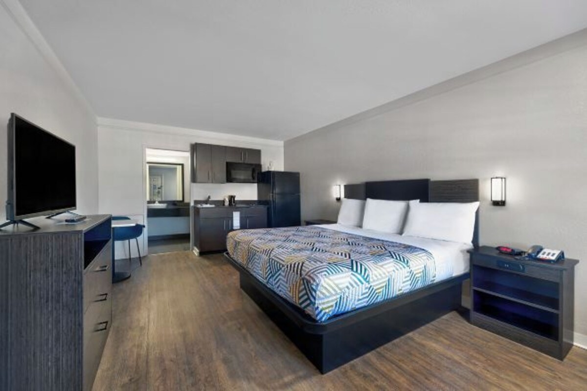 Une chambre d’hôtel moderne équipée d’un grand lit, d’un bureau, d’une télévision et d’une kitchenette.