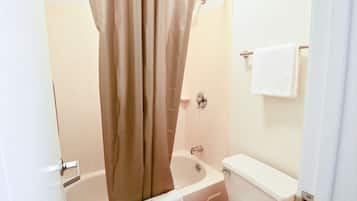 A bathroom with a bathtub, toilet, and a shower curtain.