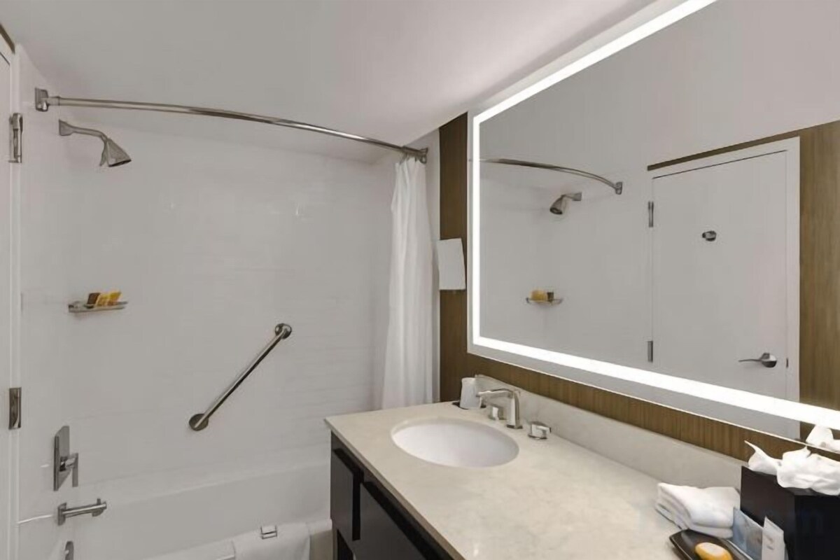 Un baño moderno con cabina de ducha, un espejo grande y tocador con lavabo.