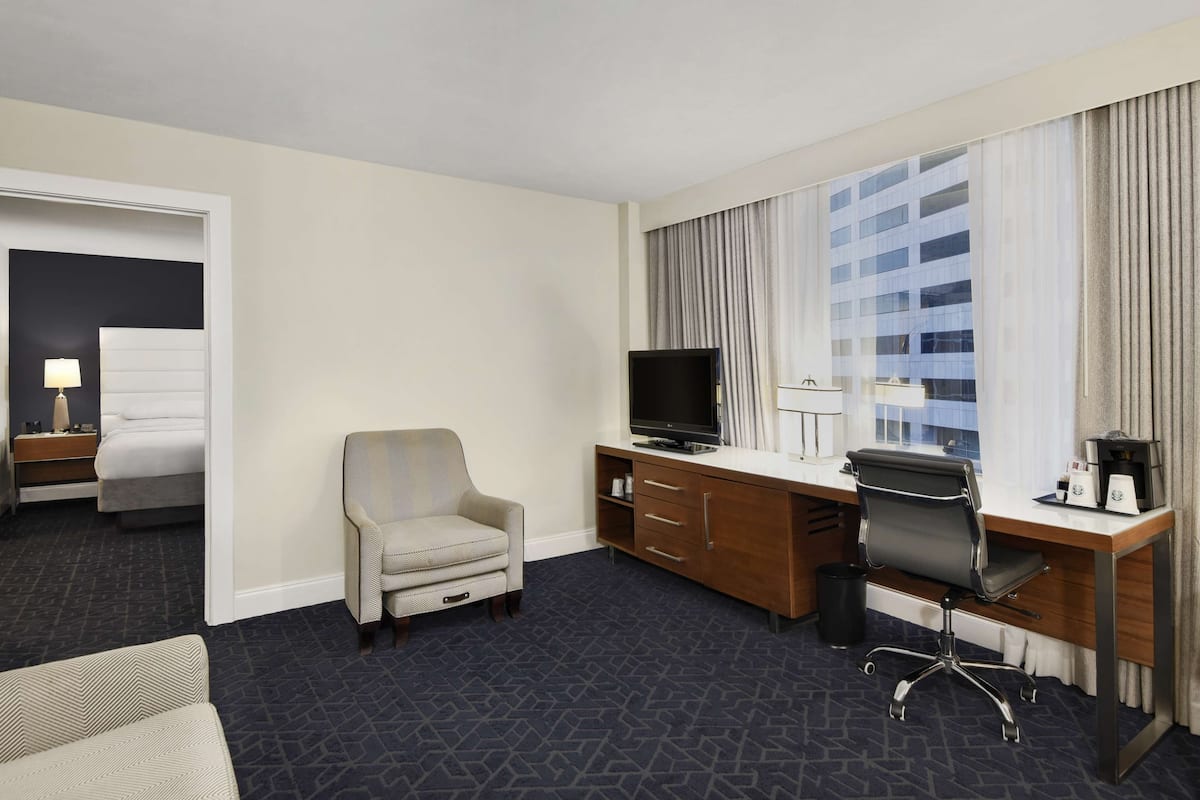 Une chambre d’hôtel avec un lit, un bureau avec un ordinateur, une télévision et une chaise.