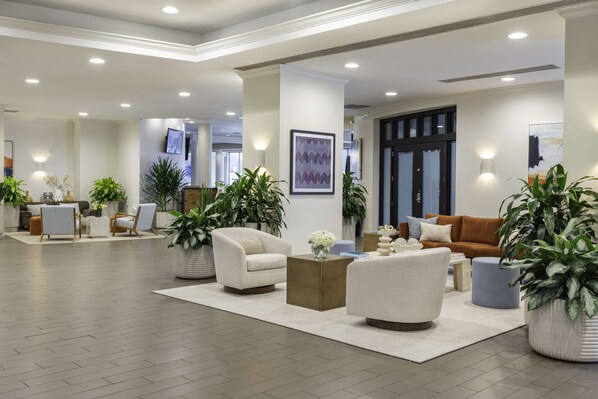 Een ruime lobby met een modern design, met een combinatie van zitgedeeltes en een receptiebalie.