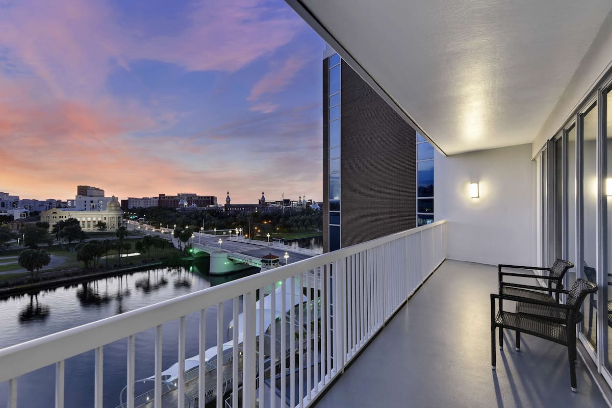 Un balcon offrant une vue sur le paysage urbain au crépuscule, avec une rivière et un pont.