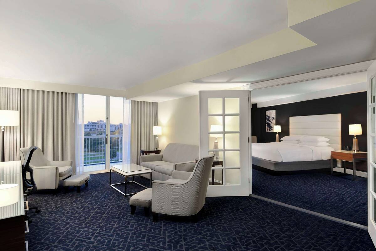 Une chambre d’hôtel avec un lit, un canapé, une chaise, un bureau et une vue sur la ville.