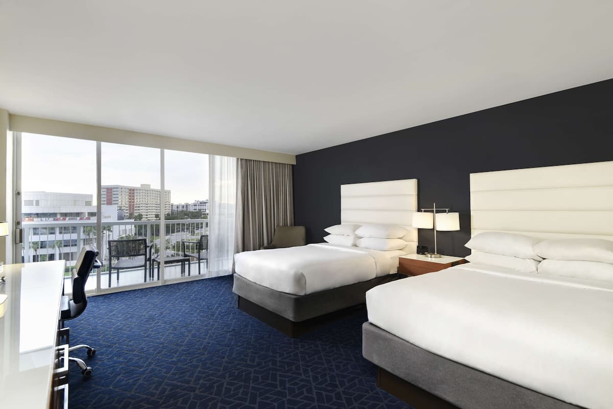 Une chambre d’hôtel avec deux lits, un bureau et une chaise.