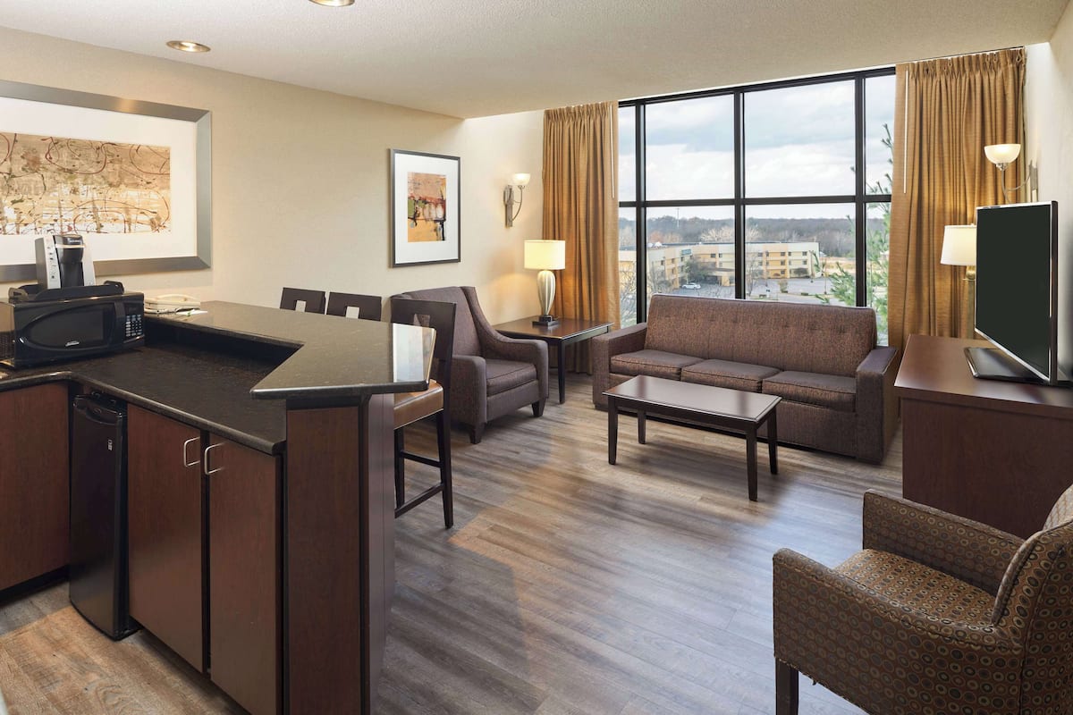 Habitación de hotel con comedor, sofá, televisor y vistas a la ciudad.