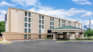 A multi-story hotel with a covered entrance, a parking lot, and flags. - Comfort Inn Chester - Richmond South (Chester)