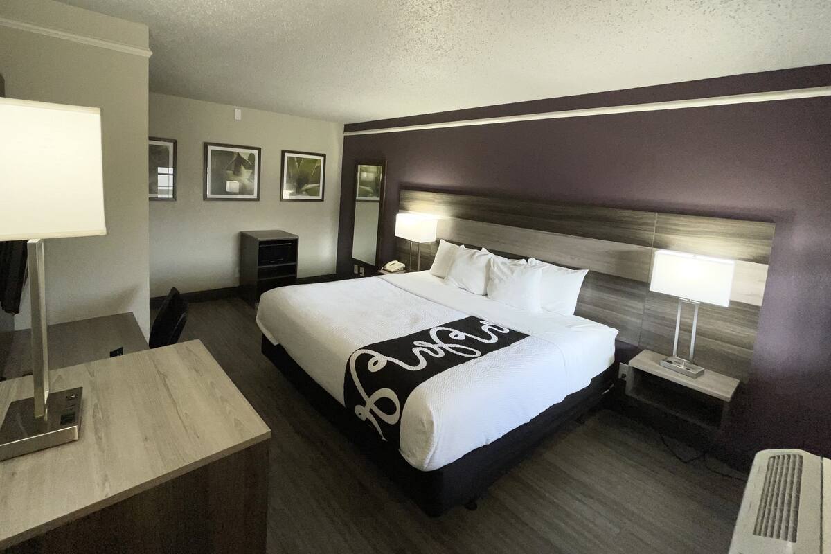 A hotel room with a large bed, bedside lamps, a desk, and a chair.