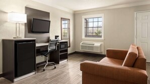 Un espace de vie compact comprenant un bureau, une chaise, une télévision et un canapé.