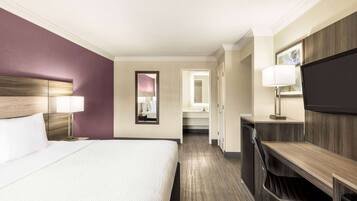 Een hotelkamer met een groot bed, een bureau, een televisie en een spiegel.