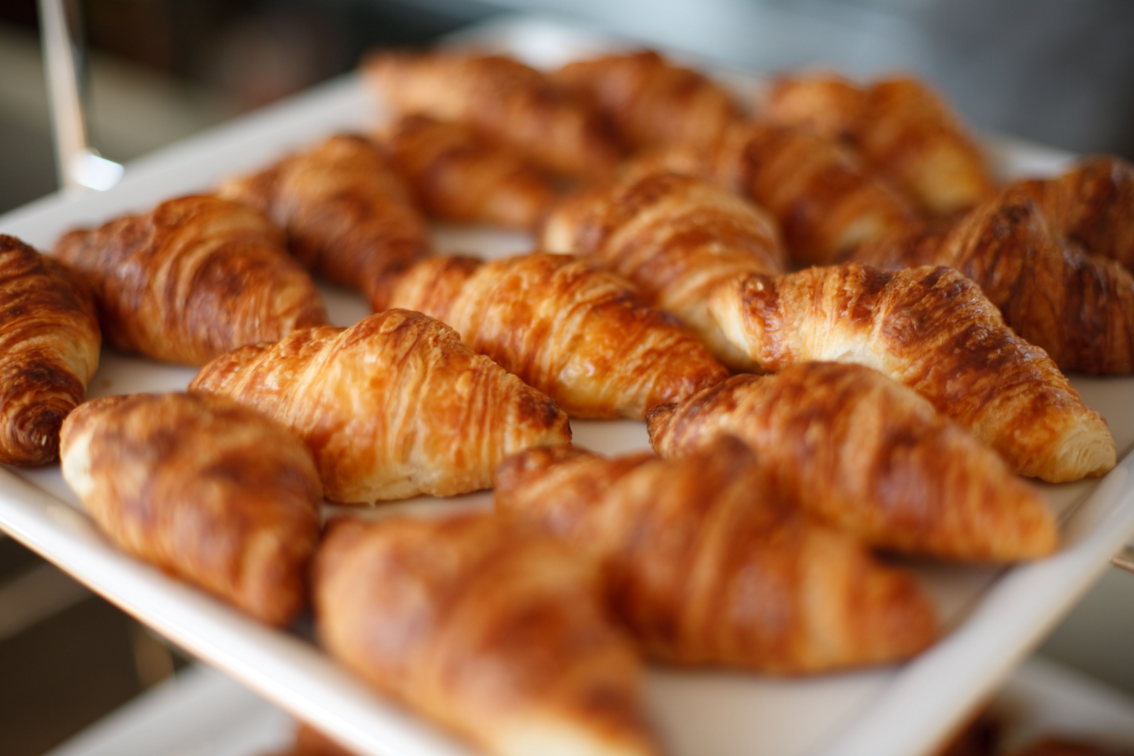 Een schaal met goudbruine croissants, gerangschikt op een wit bord.