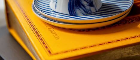 A teapot on a saucer and a book with a yellow cover.