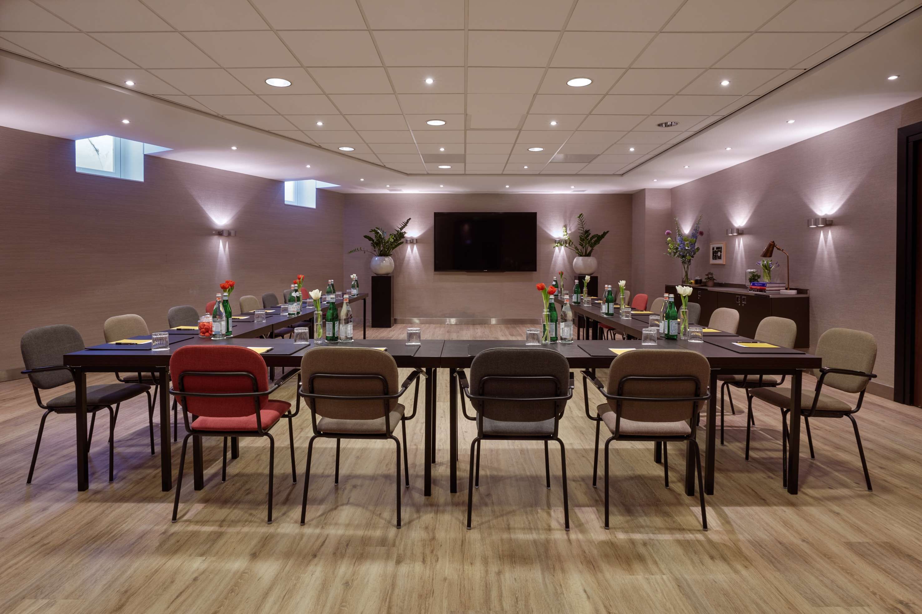 A conference room with a long table, multiple chairs, and a large screen.