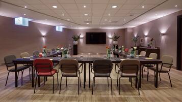 A conference room with a long table, multiple chairs, and a large screen.