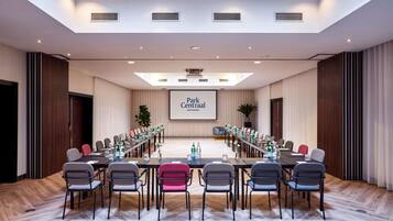 A conference room with a long table, chairs, a projector screen, and a large screen displaying "Park Centraal Amsterdam".