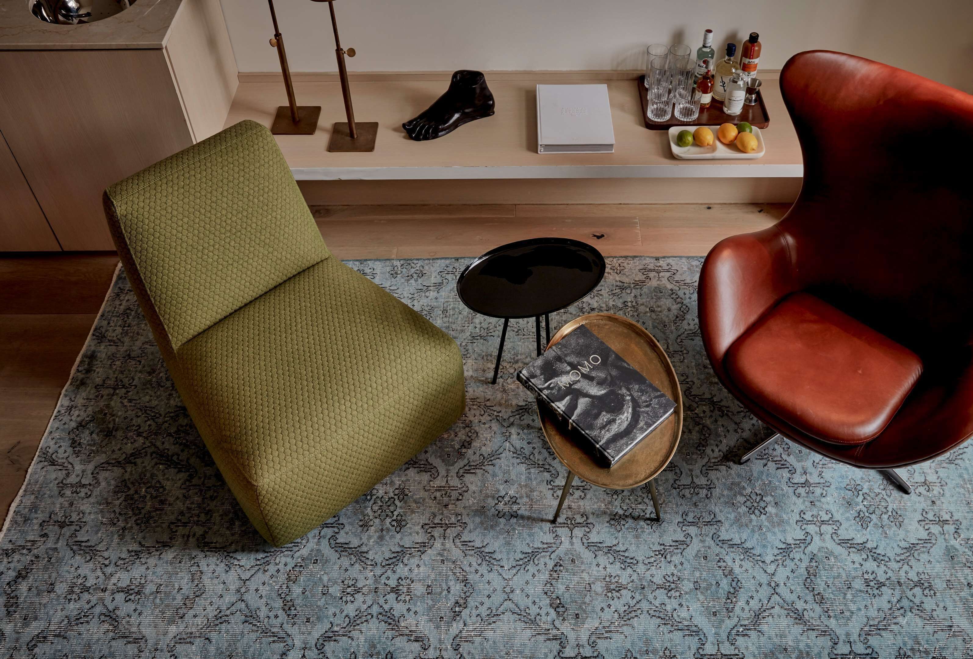 Ein modernes Wohnzimmer mit einem grünen Sessel, einem roten Stuhl, einem kleinen runden Tisch und einer Bank.