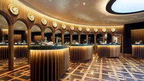 Eine moderne Hotelhalle mit einer runden Lounge, Holzvertäfelung und einem gemusterten Boden.