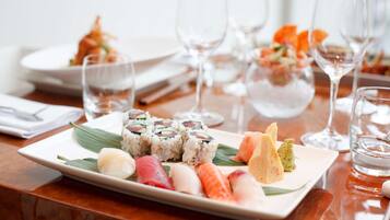 Een bord sushi met verschillende soorten sushi en sashimi, vergezeld van een glas water en een wijnglas.