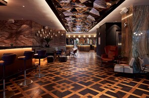 A modern lobby with a geometric patterned floor, a reception area with a marble wall, and a variety of seating options including bar stools and armchairs. - Park Centraal Amsterdam, part of Sircle Collection (Amsterdam)