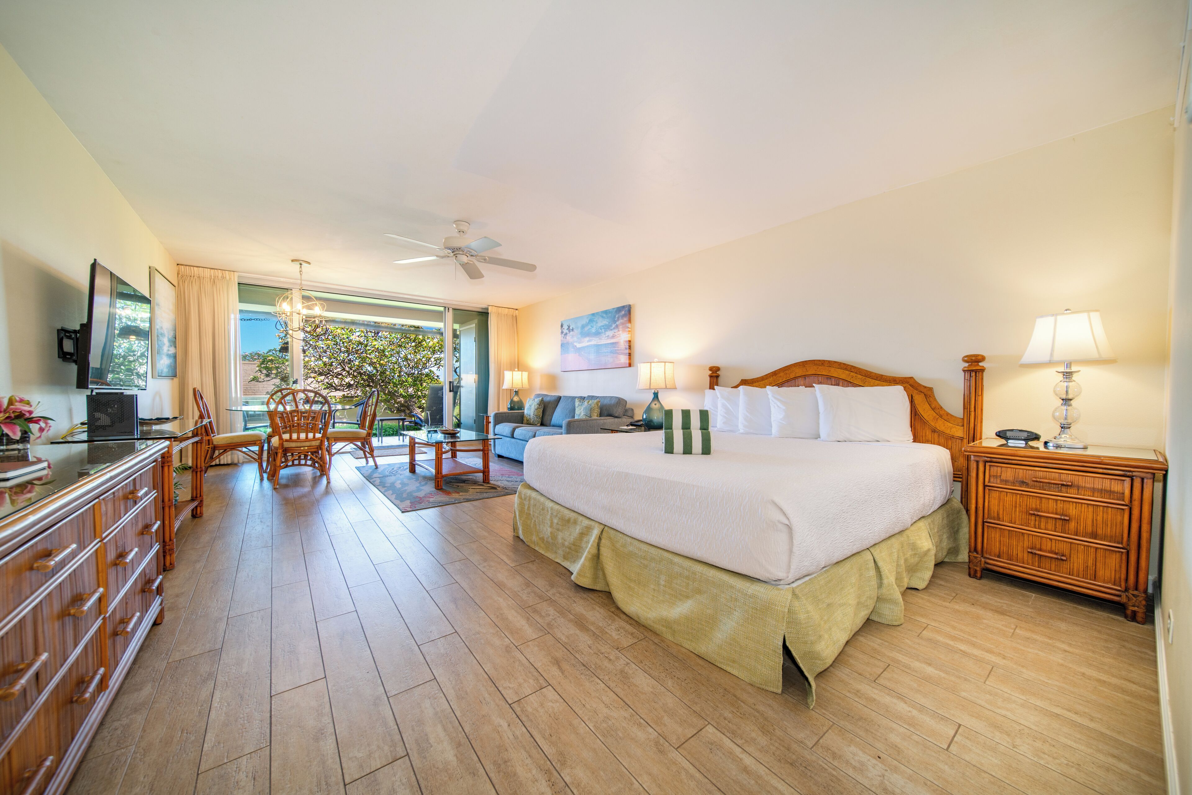 Ein geräumiges Schlafzimmer mit einem großen Bett, einer Holzkommode, einem Fernseher und Blick ins Freie.
