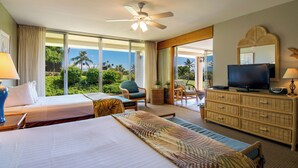 A hotel room with a bed, a television, a ceiling fan, and a view of the outdoors.