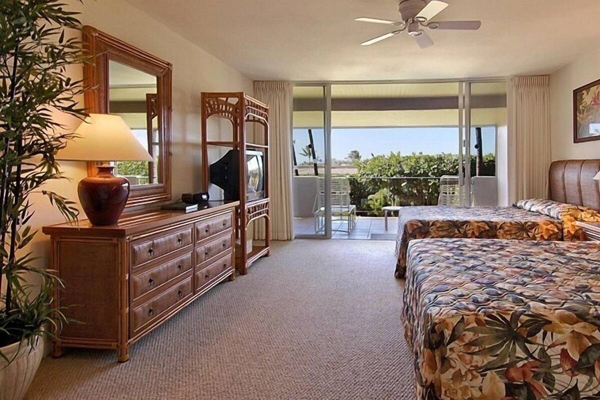 Quarto de hotel com uma cama grande, penteadeira, espelho e varanda com vista.