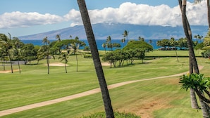 A golf course with a clear view of the ocean and a mountain in the background.