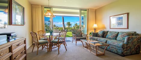 Ein Hotelzimmer mit Balkon, einer Sitzecke, einem Esstisch mit Stühlen und einem Fernseher.