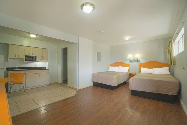 Une chambre d’hôtel avec deux lits, une kitchenette et une salle de bain.