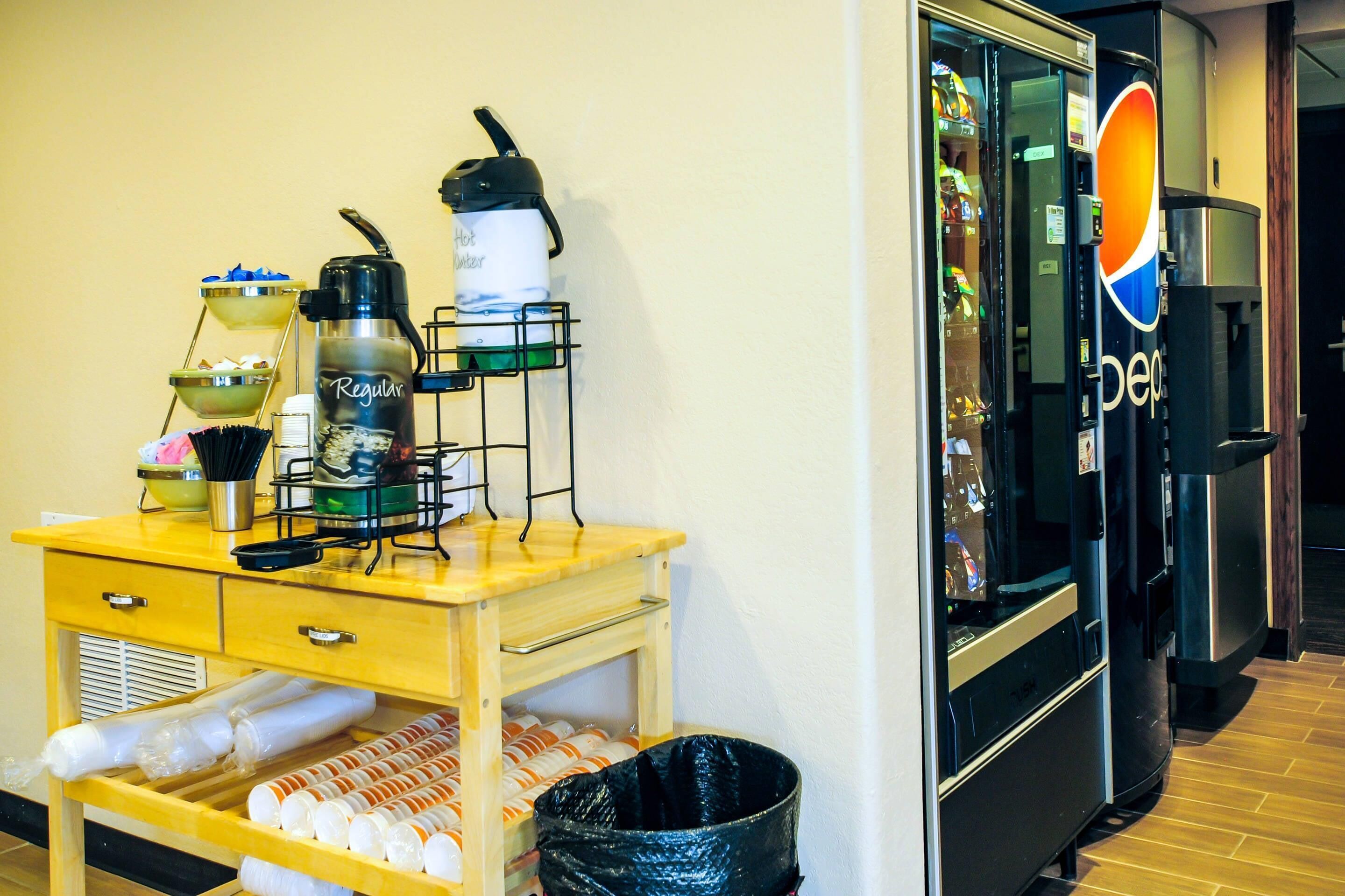 A hotel room with a kitchenette, a refrigerator, a coffee machine, and a trash bin.
