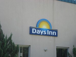 A Days Inn sign on a building facade with two windows and a security camera.