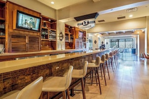 Una zona de bar con una barra larga, estantes de madera y taburetes.
