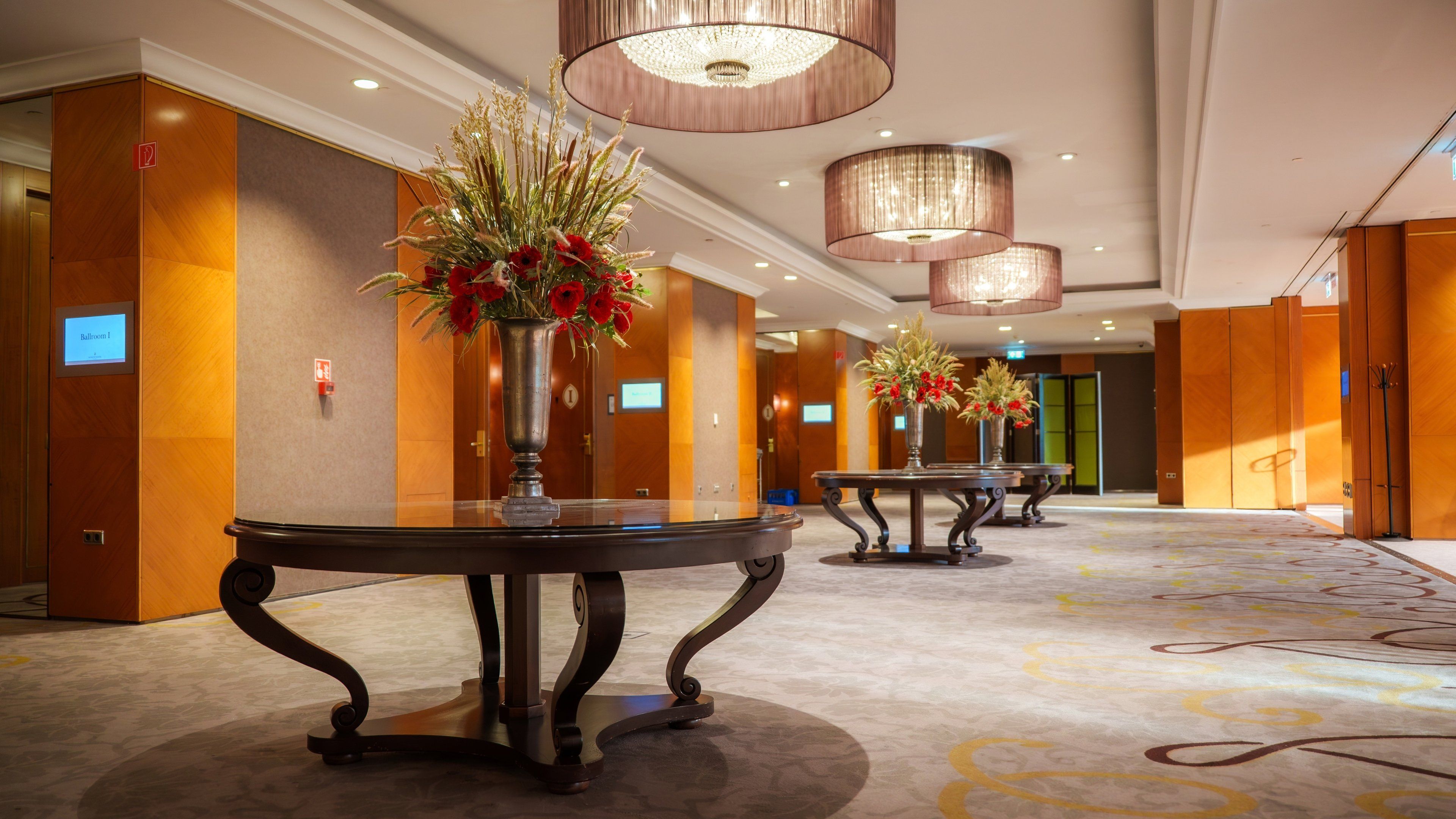 Un hall de hotel con piso alfombrado, paredes de madera y una mesa de recepción.