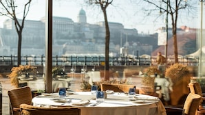 A dining table set for two with a cityscape view through large windows. - InterContinental Budapest by IHG (Budapest)