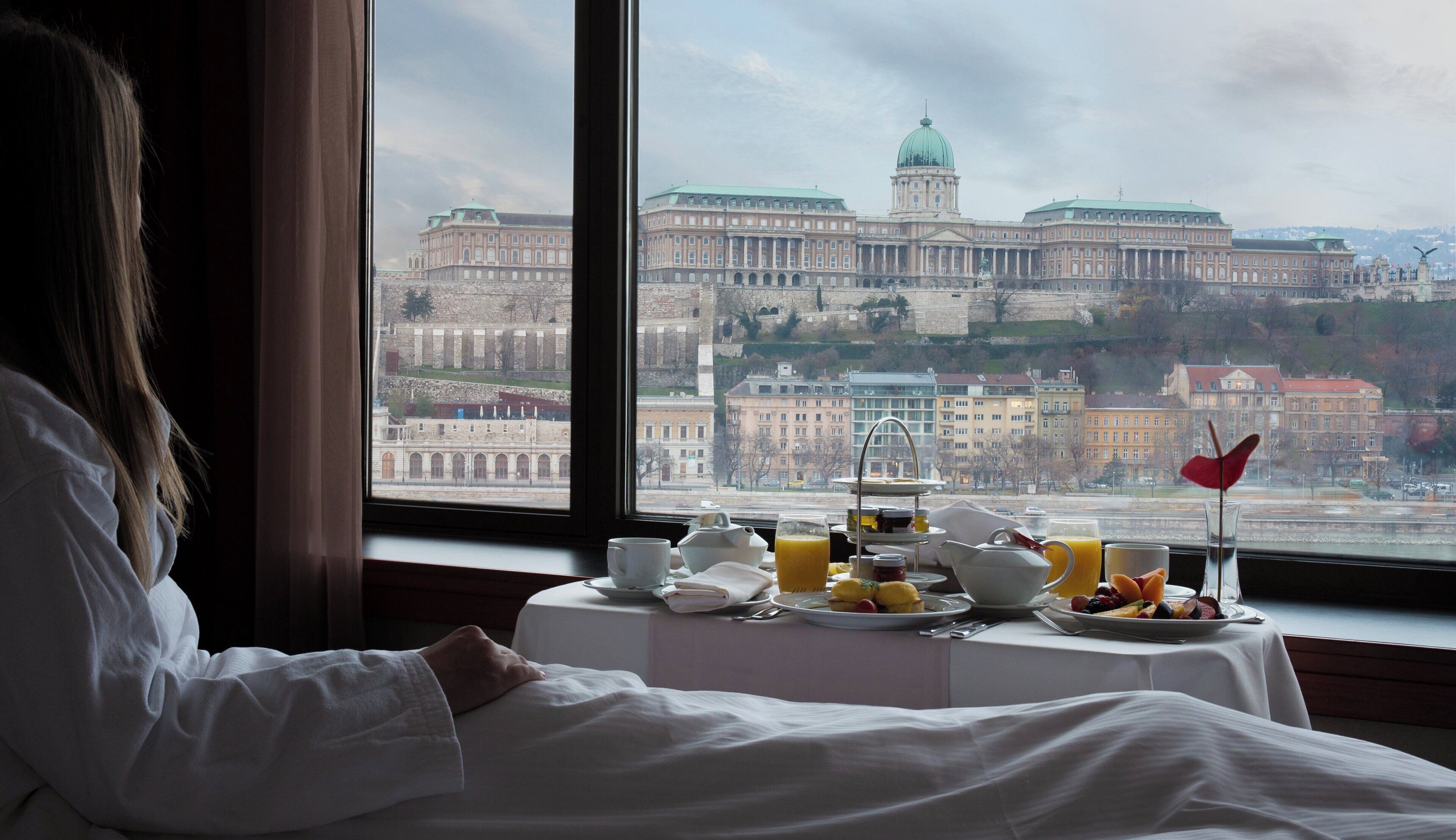 A hotel room with a view of a large historic building through a window.