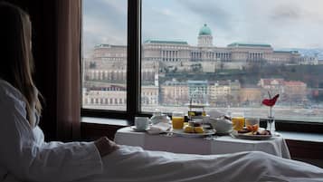 A hotel room with a view of a large historic building through a window.