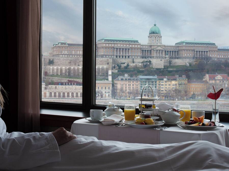 A hotel room with a view of a large historic building through a window.