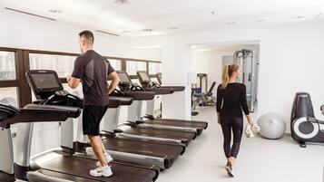 Un gimnasio con cintas de correr, balones de ejercicio y máquinas de pesas.