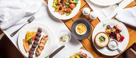 A dining table with various dishes, including grilled meat, salads, and dips.