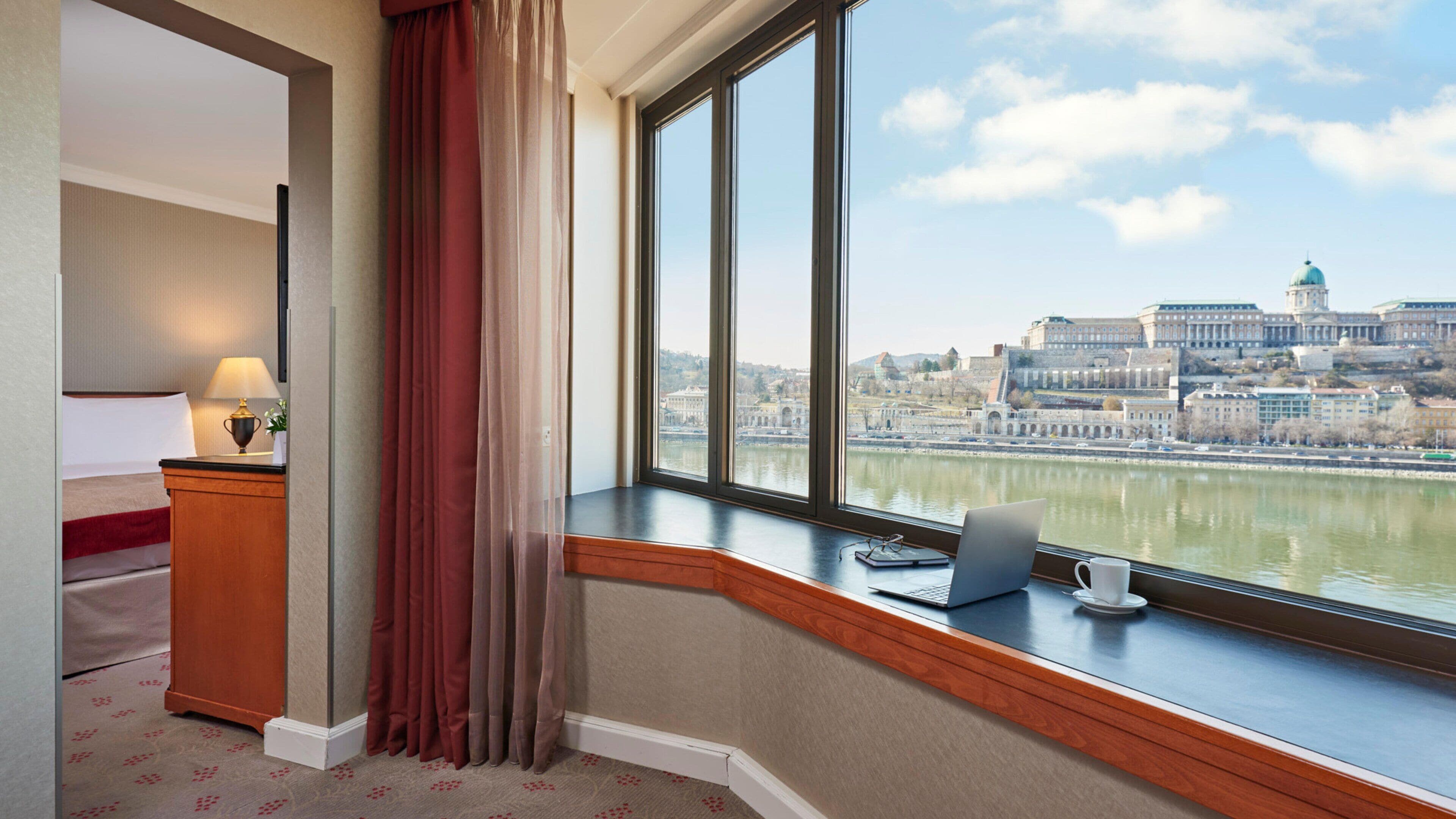 Hotelkamer met een groot raam met uitzicht op een stadslandschap en rivier.